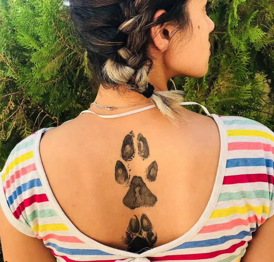 large and small paw print tattoo on the back of the woman