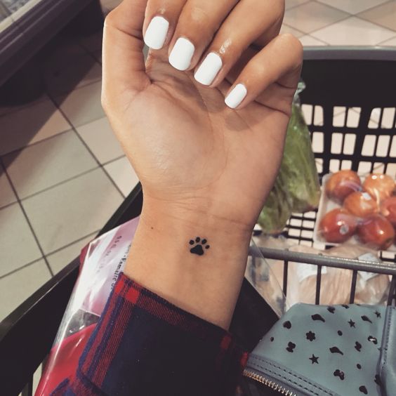 small paw print tattoo on the wrist of the woman