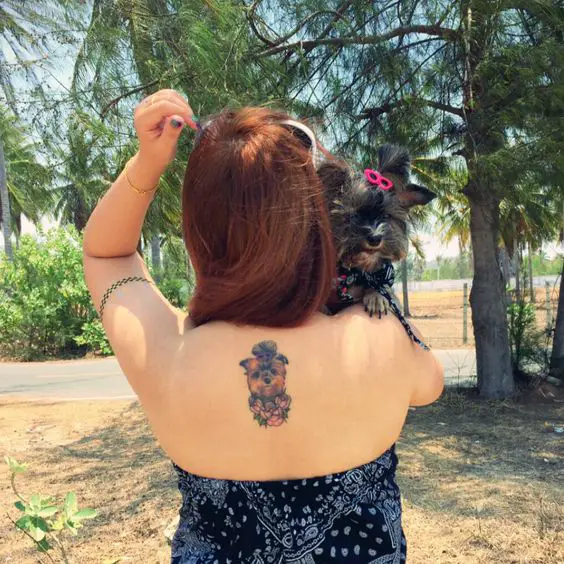 a cute yorkie tattoo on the back of the woman carrying her yorkie dog