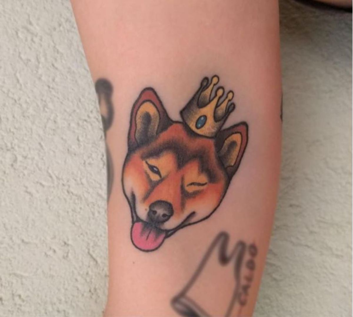 face of Shiba Inu winking and wearing a crown tattoo