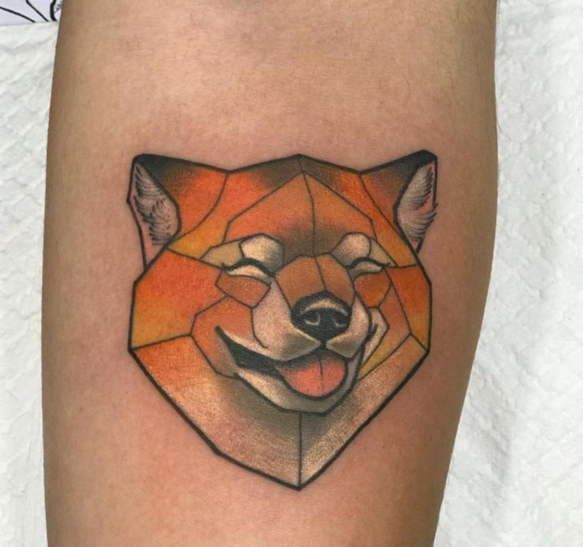 smiling with no eyes Shiba Inu in geometric design tattoo on the forearm