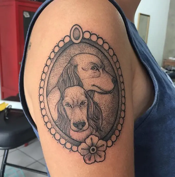 two faces of a Cocker Spaniel inside an oblong frame Tattoo on the shoulder