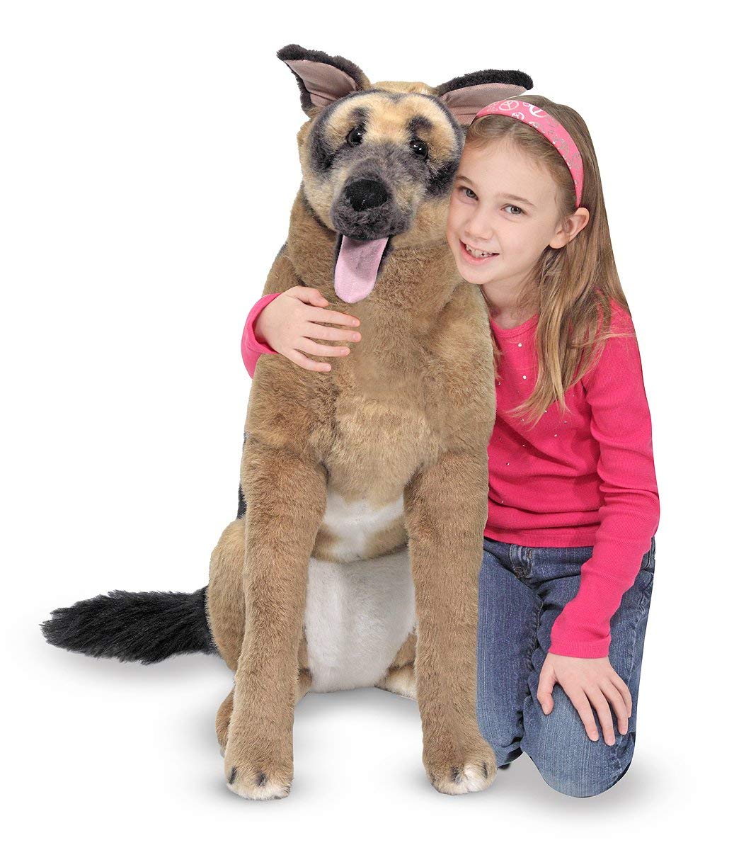 a girl kneeling on the floor while embracing a life-sized german shepherd plush