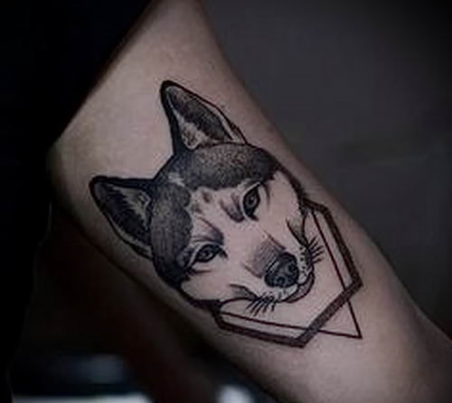 face of a Husky inside a hexagon and upside down triangle tattoo on the biceps of a man