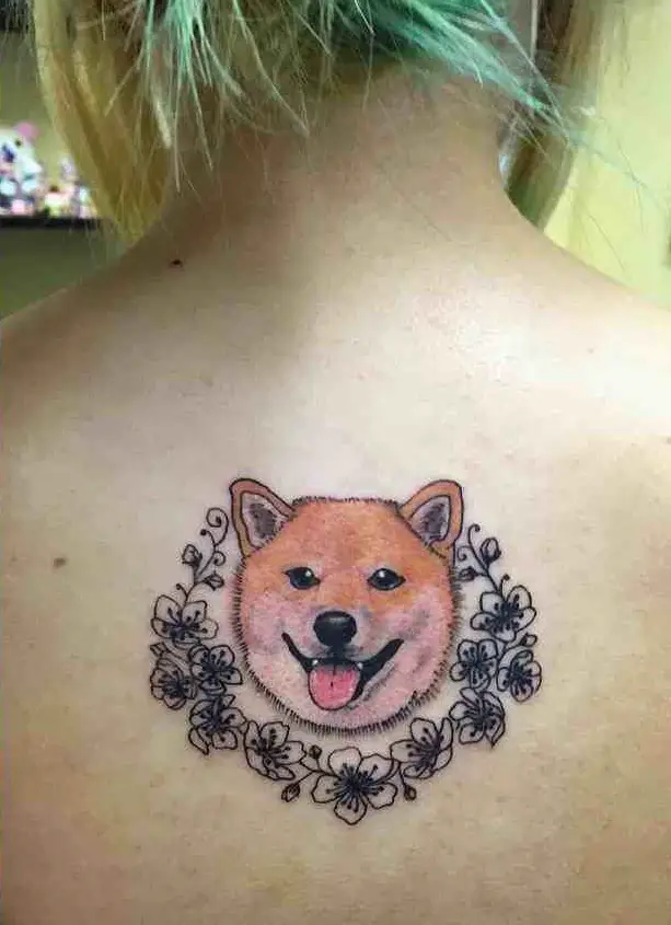smiling face of Shiba Inu with flowers around tattoo on the back