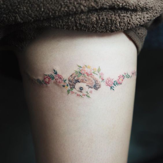 arm tattooed with sleeping dog with curved lines of flowers accross