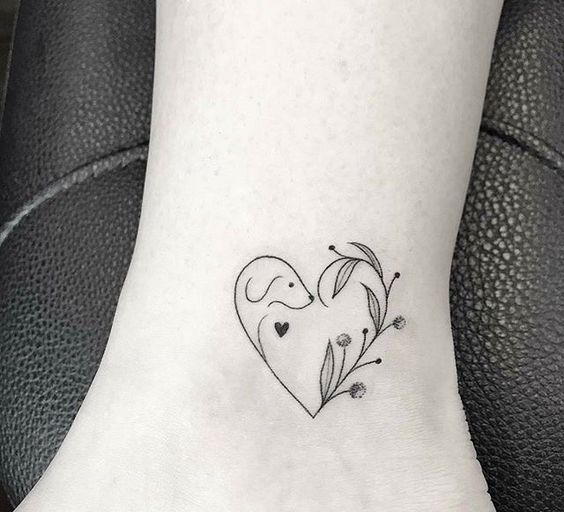 outline heart shaped with dog and plants tattoo on the ankle
