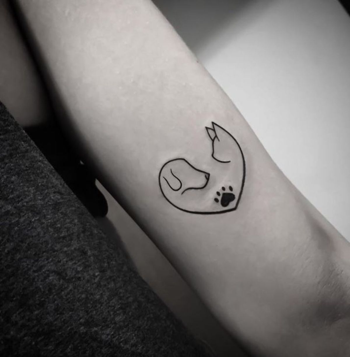 outline dog and cat forming a heart tattoo on the arms