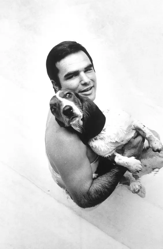 black and white photo of Burt Reynolds holding its Basset Hound
