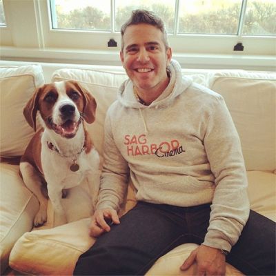 Andy Cohen sitting on the couch with his Beagle sitting next to him