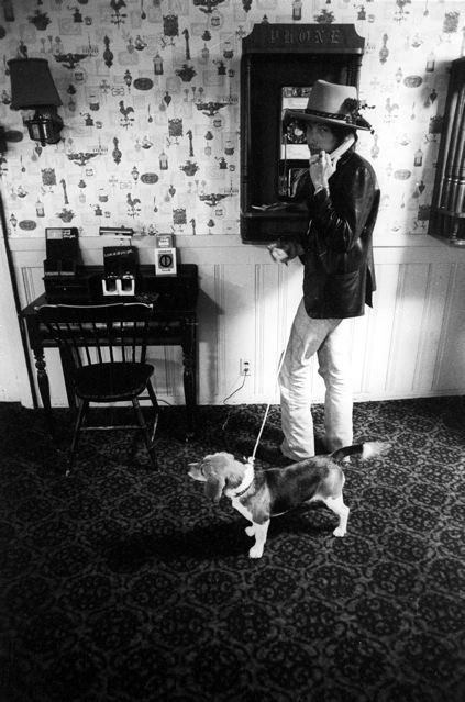 Bob Dylan talking to the phone while his Beagle is standing next to him