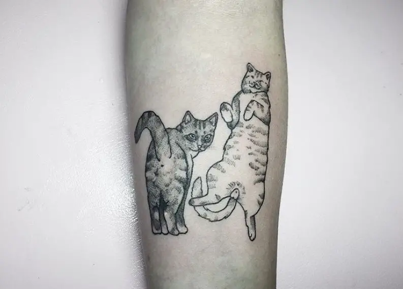 black and gray tattoo of two cats on the forearm