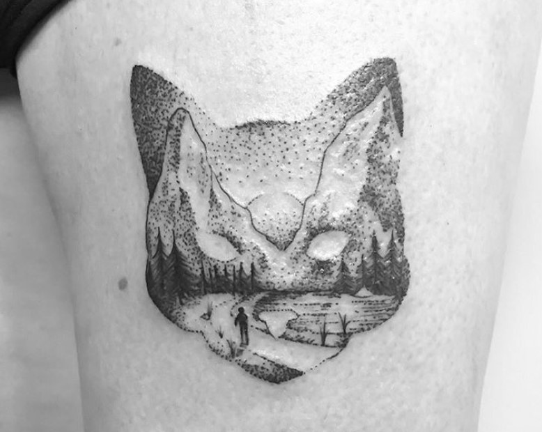 face shape of a cat with mountain landscape tattoo on thigh
