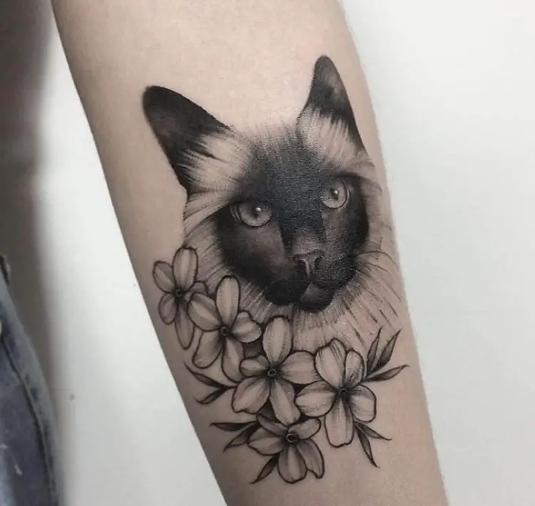 realistic face of a Black and White Cat with flowers tattoo on the forearm