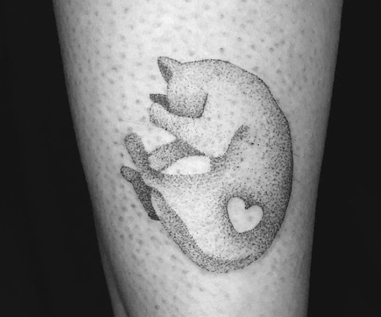 A curled up Black and White Cat tattoo on thigh