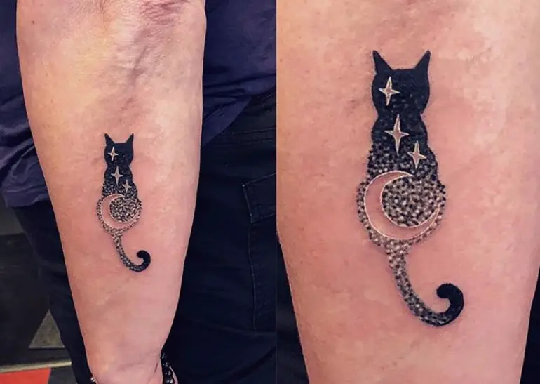 shape of a black cat with night time design tattoo on the arm