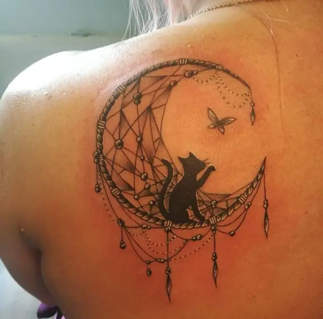 a black cat playing with a butterfly while sitting on a crescent moon tattoo on the back