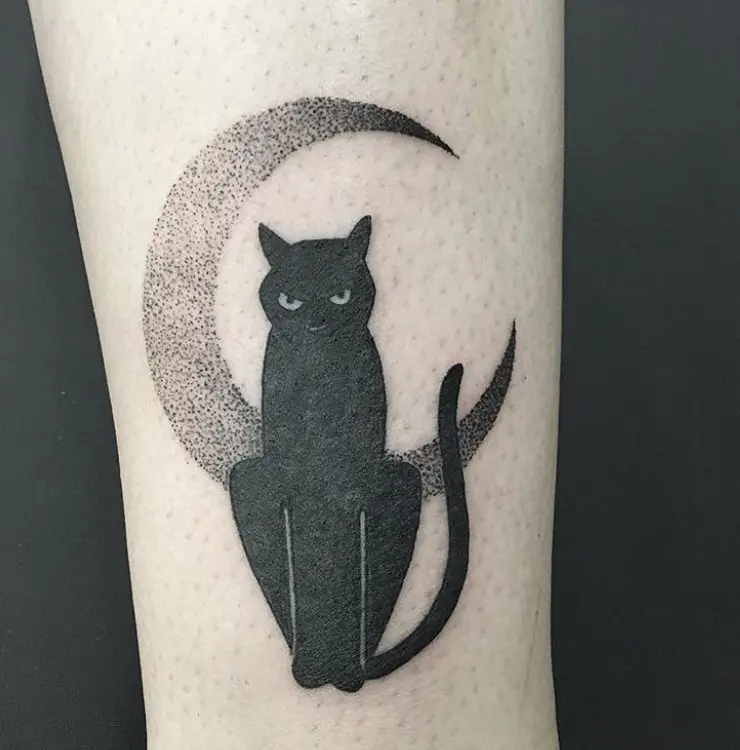 black cat with angry face while sitting on the crescent moon tattoo