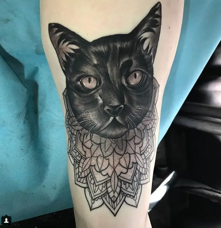 black cat's face with aztec design tattoo on legs