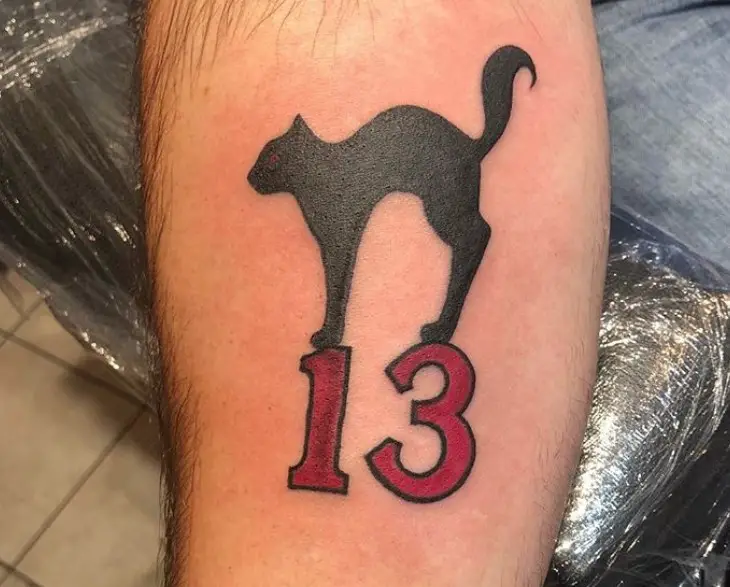 stretching black cat on top of red 13 tattoo on wrist