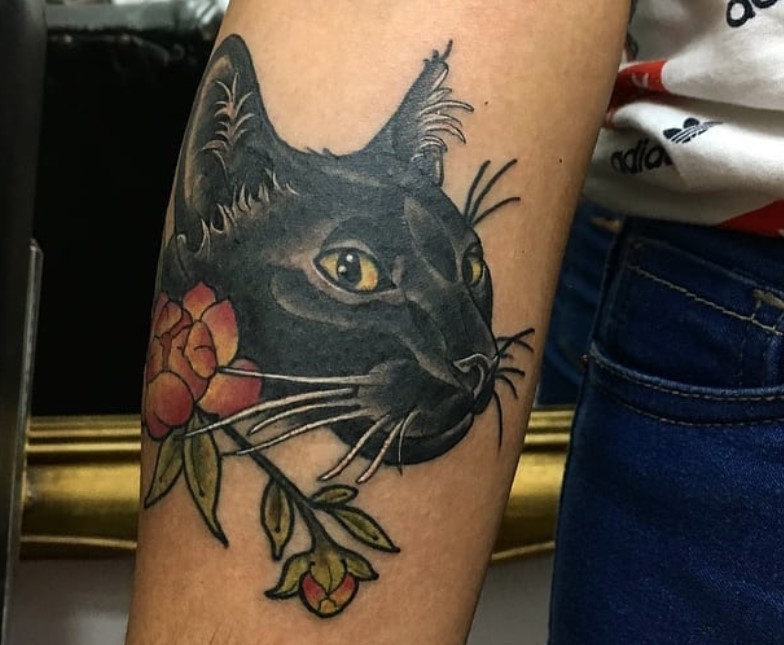 face of black cat and red flowers tattoo on arm