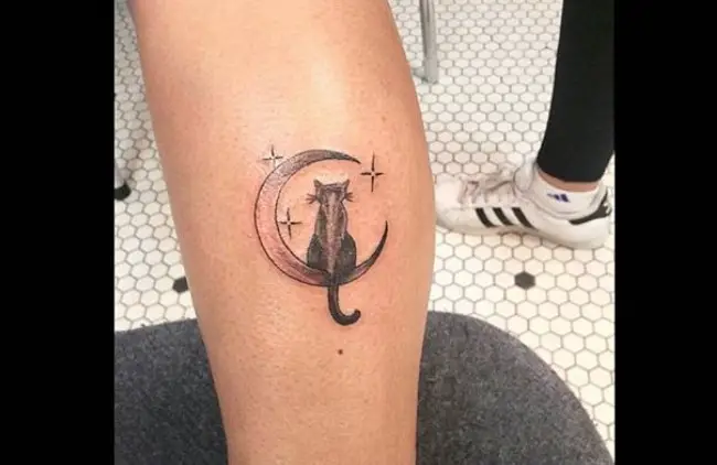 black cat sitting on the crescent moon tattoo on the forearm