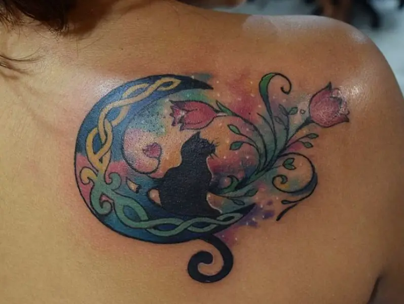 black cat sitting on a colorful watercolor crescent moon tattoo on the back
