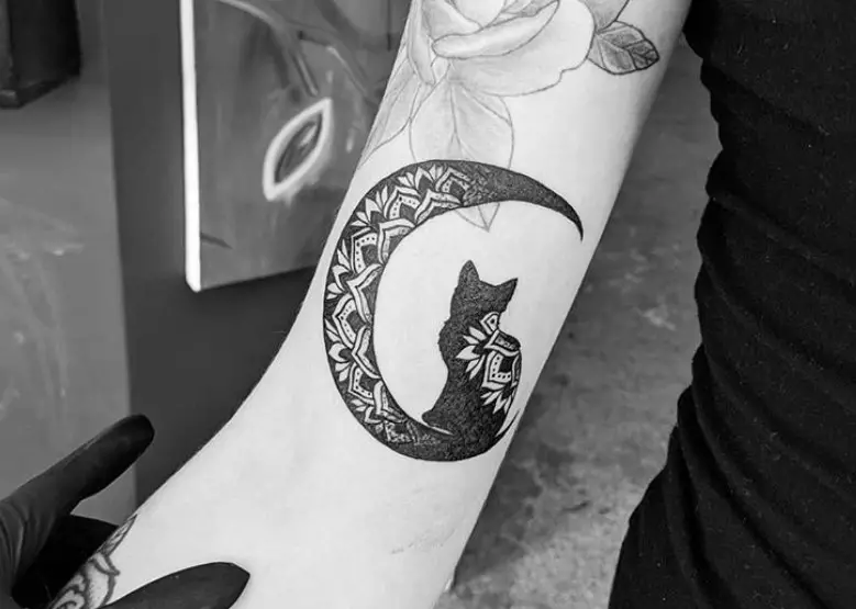 black cat sitting on the crescent moon in mandala design tattoo on the arms