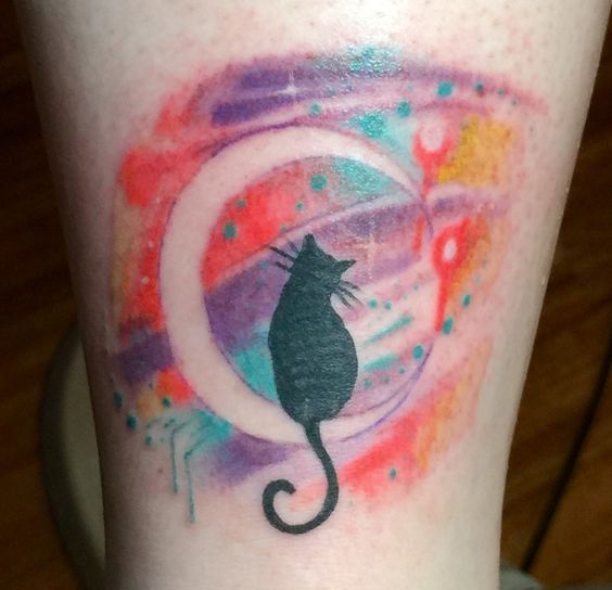 black cat on the crescent moon with a colorful watercolor background tattoo