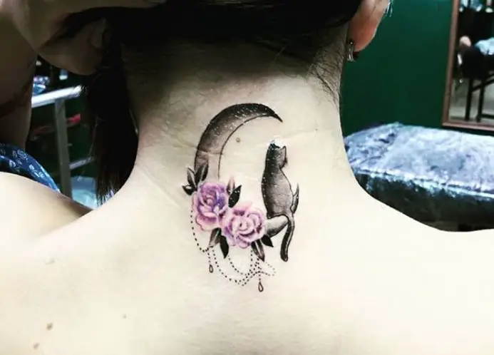 black cat sitting on the crescent moon with purple flowers tattoo on the back of the neck