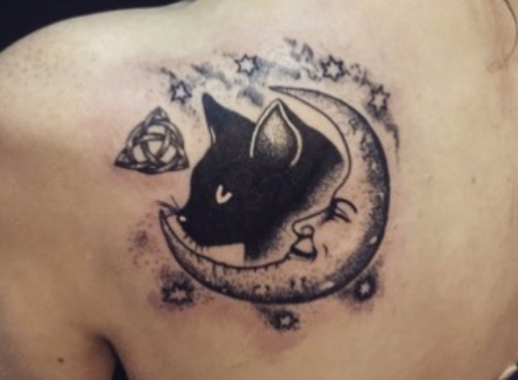 a smiling crescent moon with a black cat's face tattoo on the back