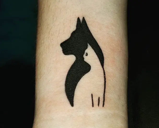 black tattoo of dog and outline of cat tattoo on the shoulders