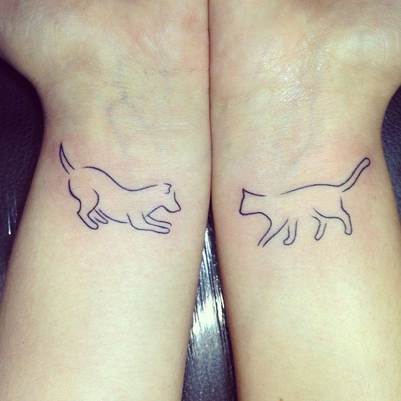 one wrist with dog tattoo and other wrist with cat tattoo