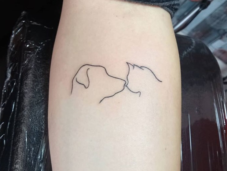 outline of dog and cat tattoo facing each other on the arms