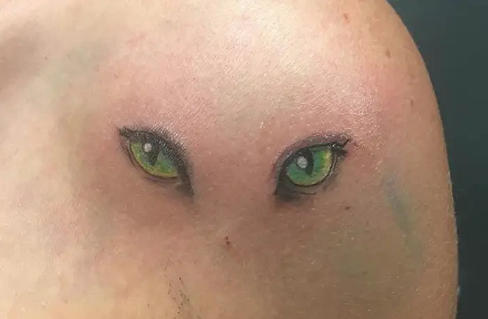 beautiful green eyes of a cat tattoo on the shoulder