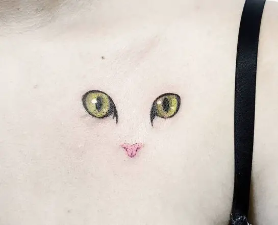 cute eyes and pink nose of a cat tattoo on the chest