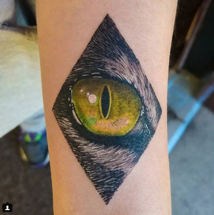 yellow Cat Eye inside a diamond shape tattoo in the forearm