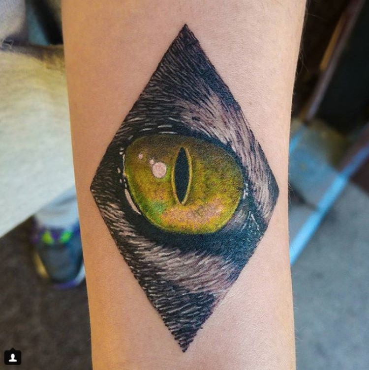 yellow Cat Eye inside a diamond shape tattoo in the forearm