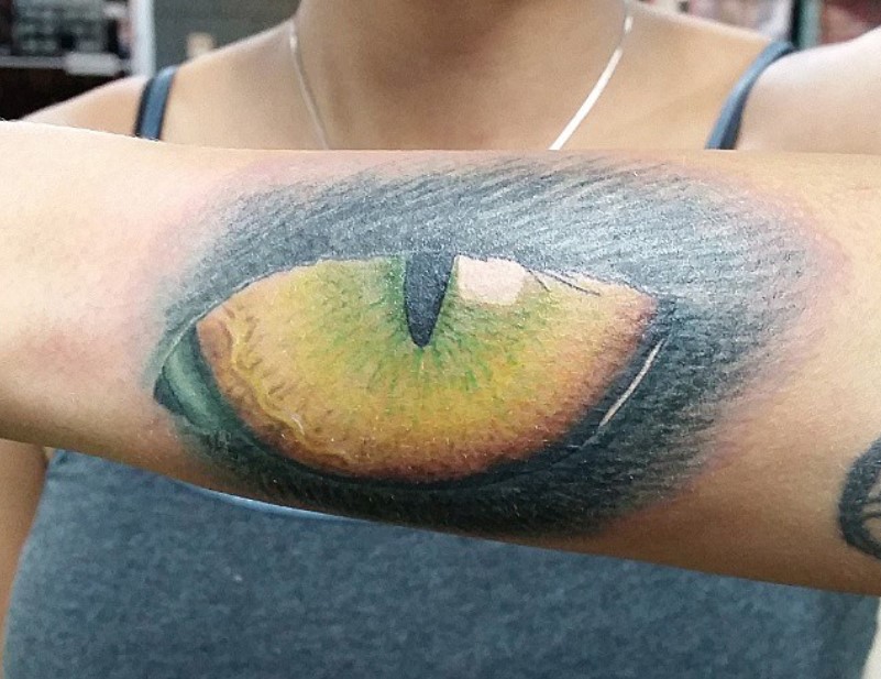 large Cat Eye tattoo on the arm of a lady