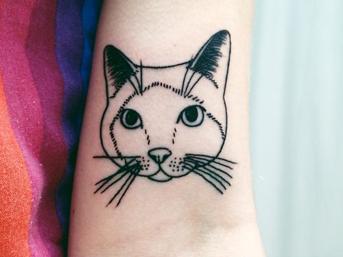 outline face of a cat tattoo on the biceps