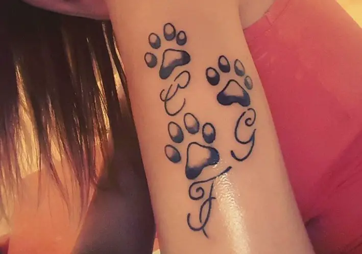 three Cat Paw Prints with cursive initials tattoo on the arm