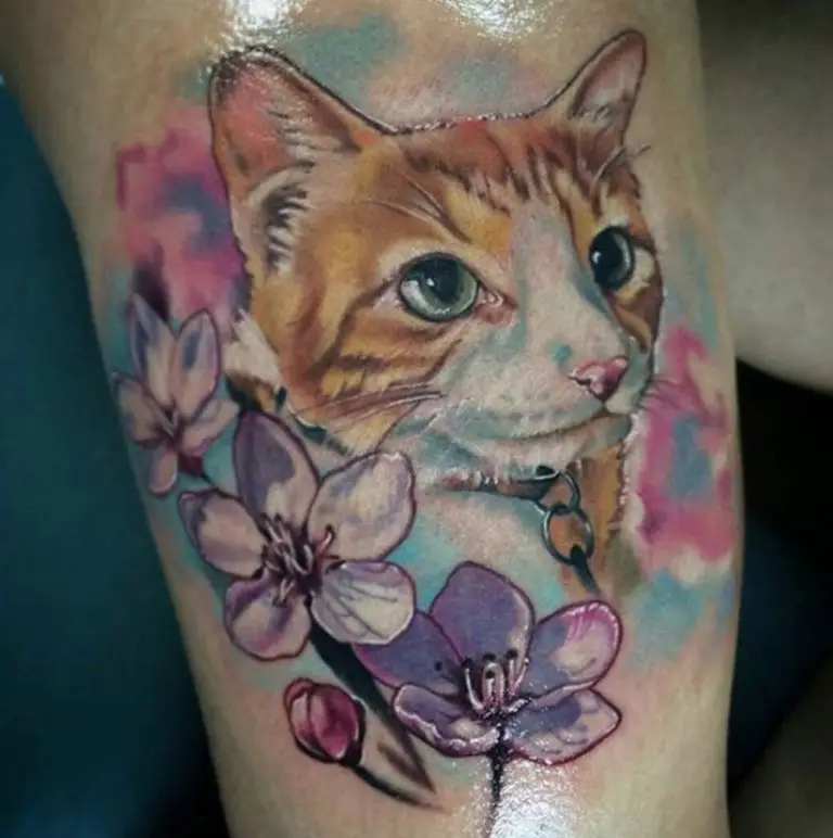 An orange and white face of a Cat Portrait with sakura flowers Tattoo on the leg