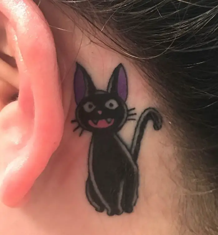 smiling black cat while sitting tattoo behind the ear