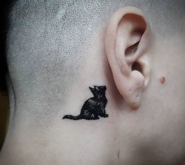 a sitting black cat looking up tattoo behind the ear a girl with shaved head