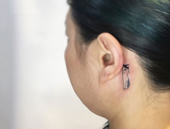 half feature of a sitting cat tattoo behind the ear of a girl