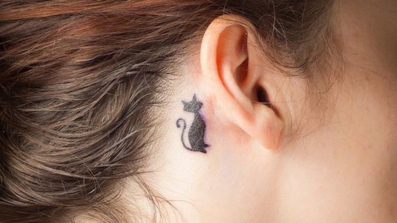 a sitting black cat tattoo behind the ear