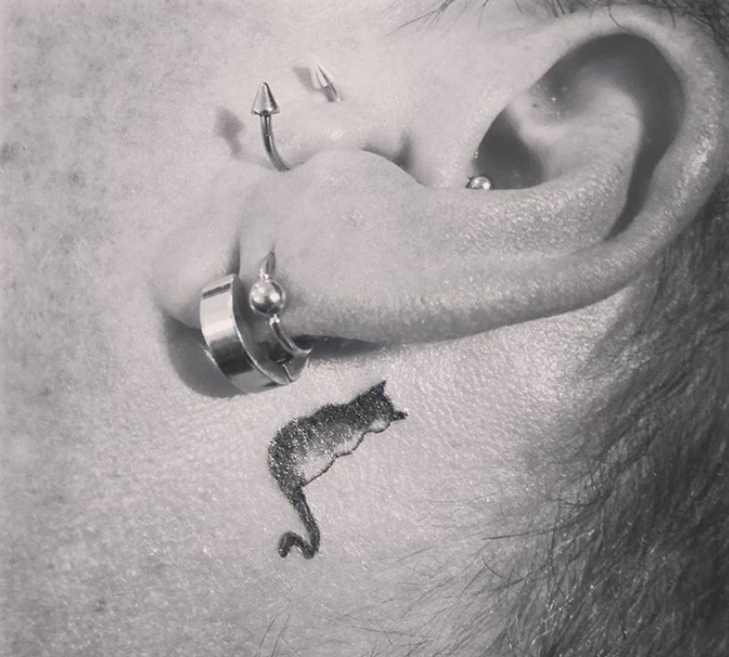 small back view of a sitting cat tattoo behind the ear of a girl