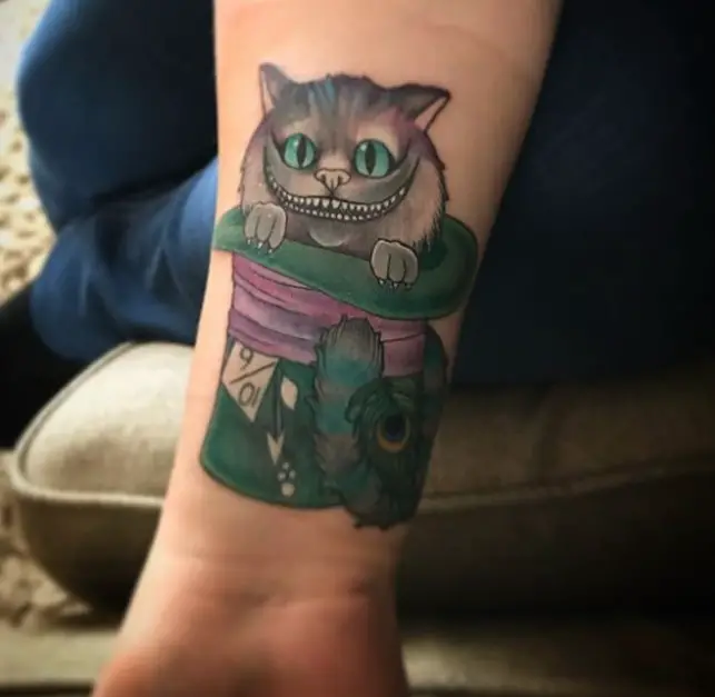 gray Cheshire Cat sitting inside the a green hat tattoo on the forearm