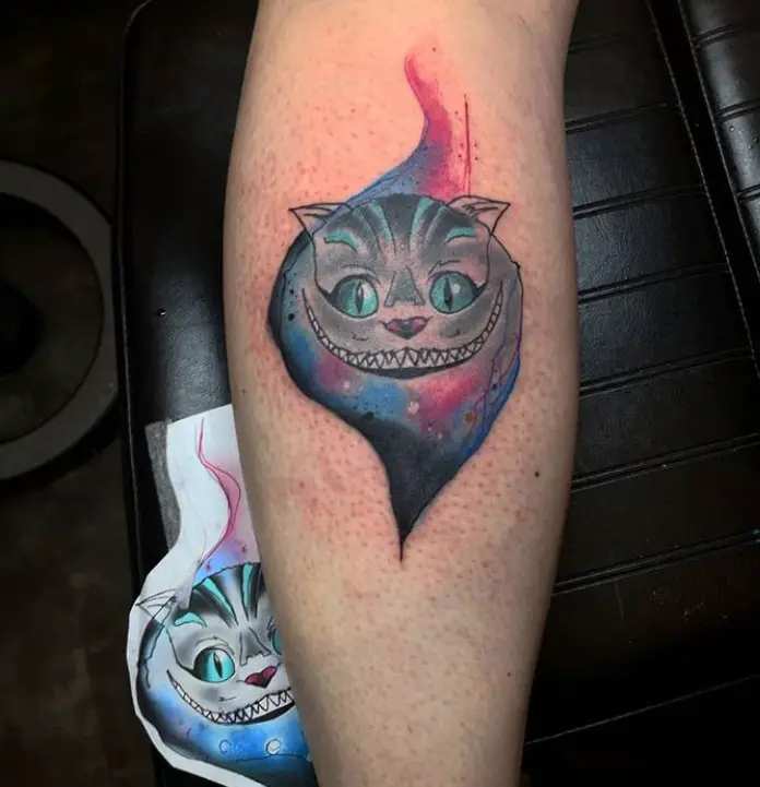 smoky blue and pink Cheshire Cat with green eyes tattoo on the forearm