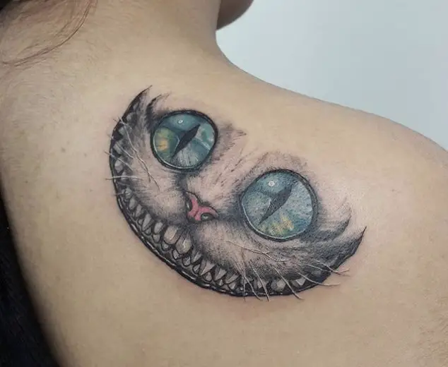 gray Cheshire Cat with pink nose and blue, and yellow eyes tattoo on the back